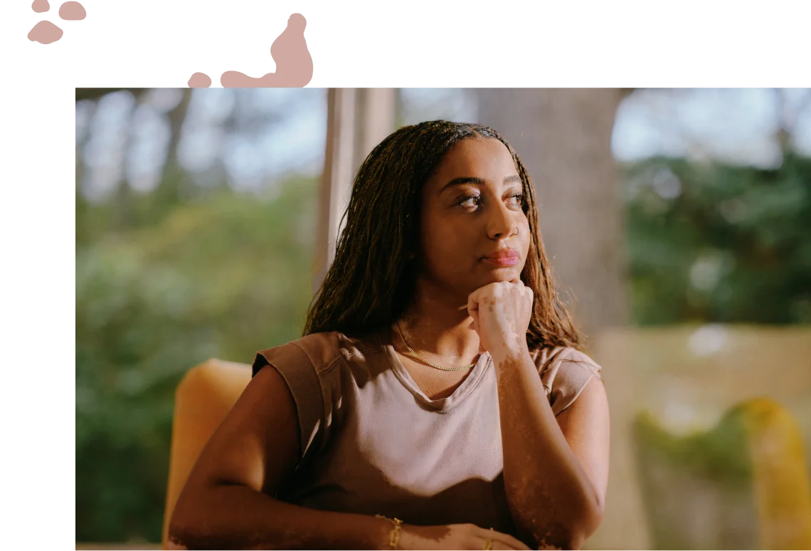 A girl sitting on a chair, resting her chin on her hand
