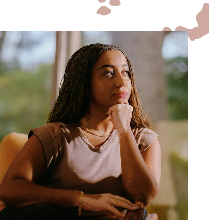 A girl sitting on a chair, resting her chin on her hand
