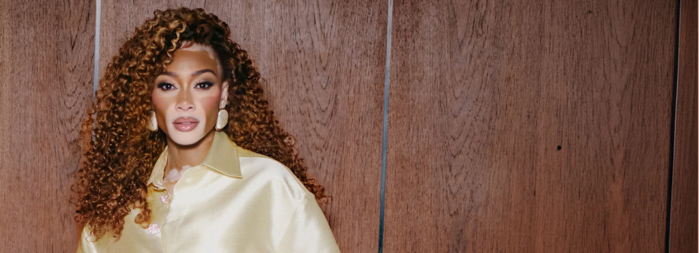 Winnie in a gold shirt against a wooden background