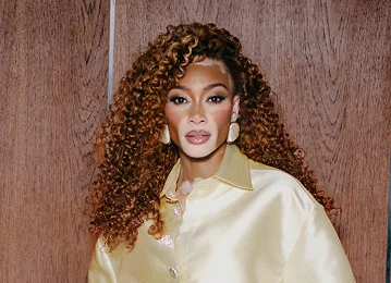 Winnie in a gold shirt against a wooden background